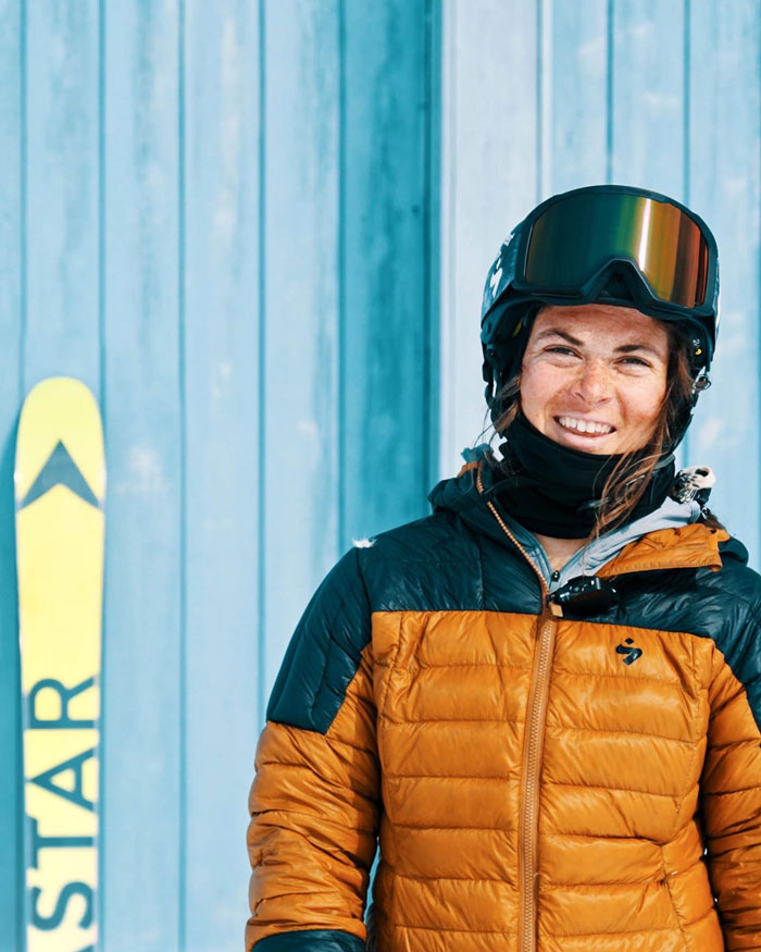 Portrait de Juliette Willmann en tenue de ski à côté de ses skis freeride